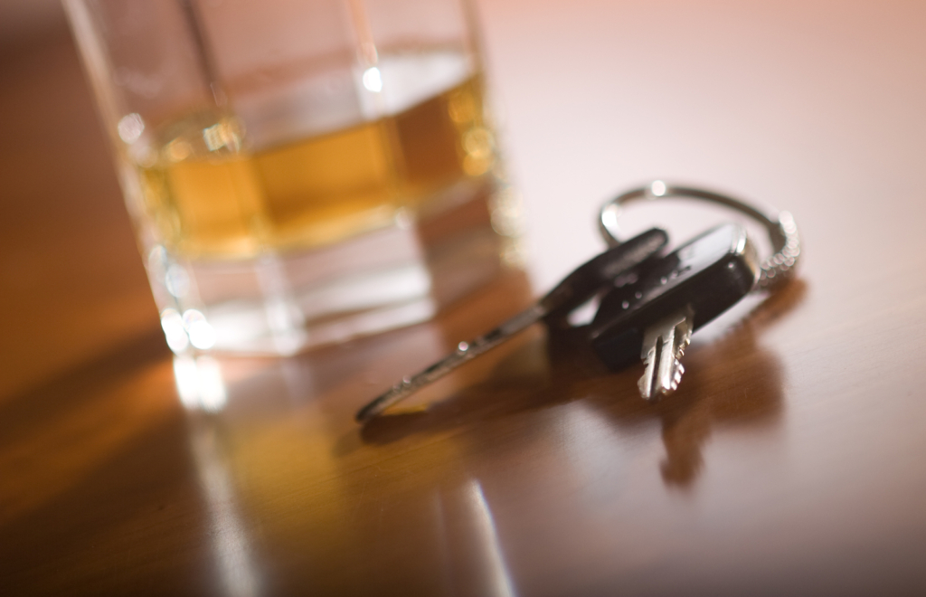 Keys on a table with a glass of alcohol.