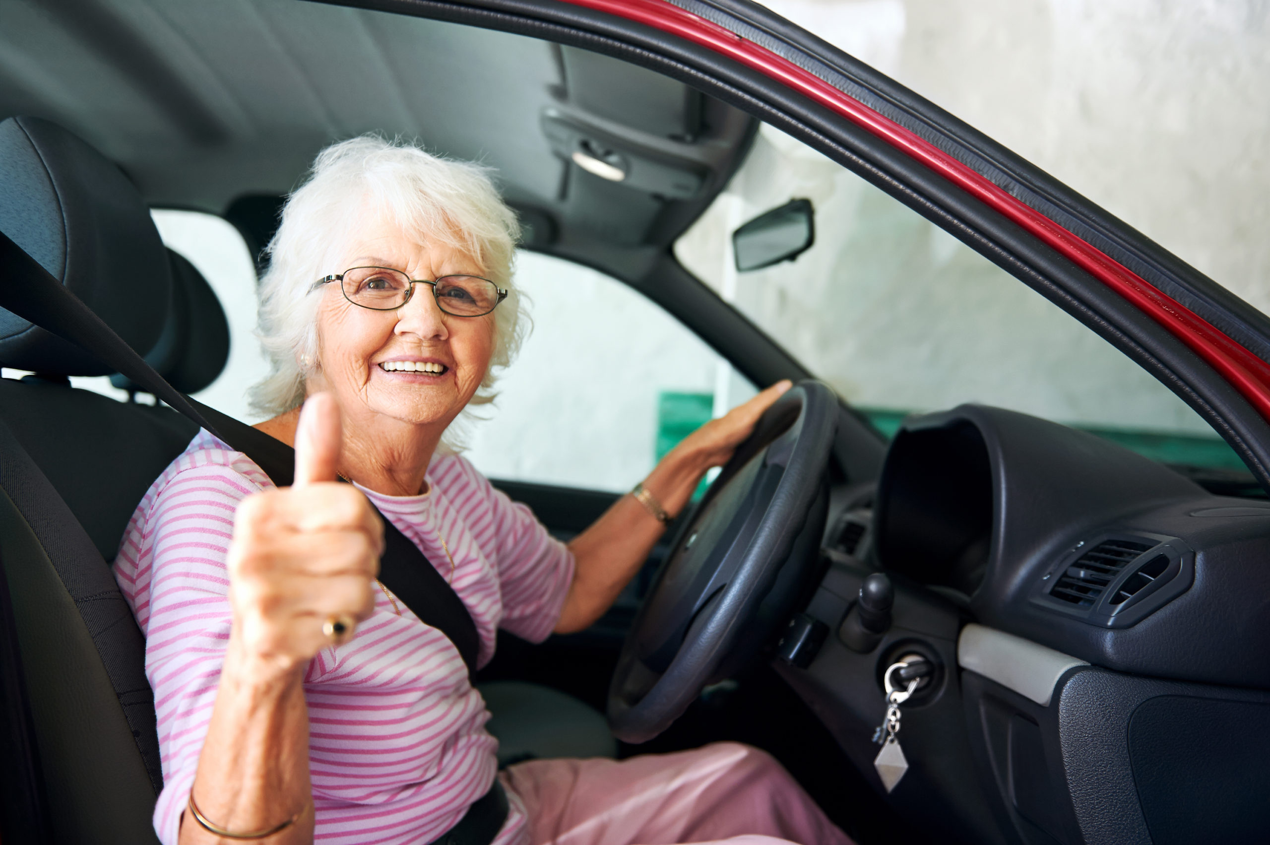 older woman sitting in the driving of a car